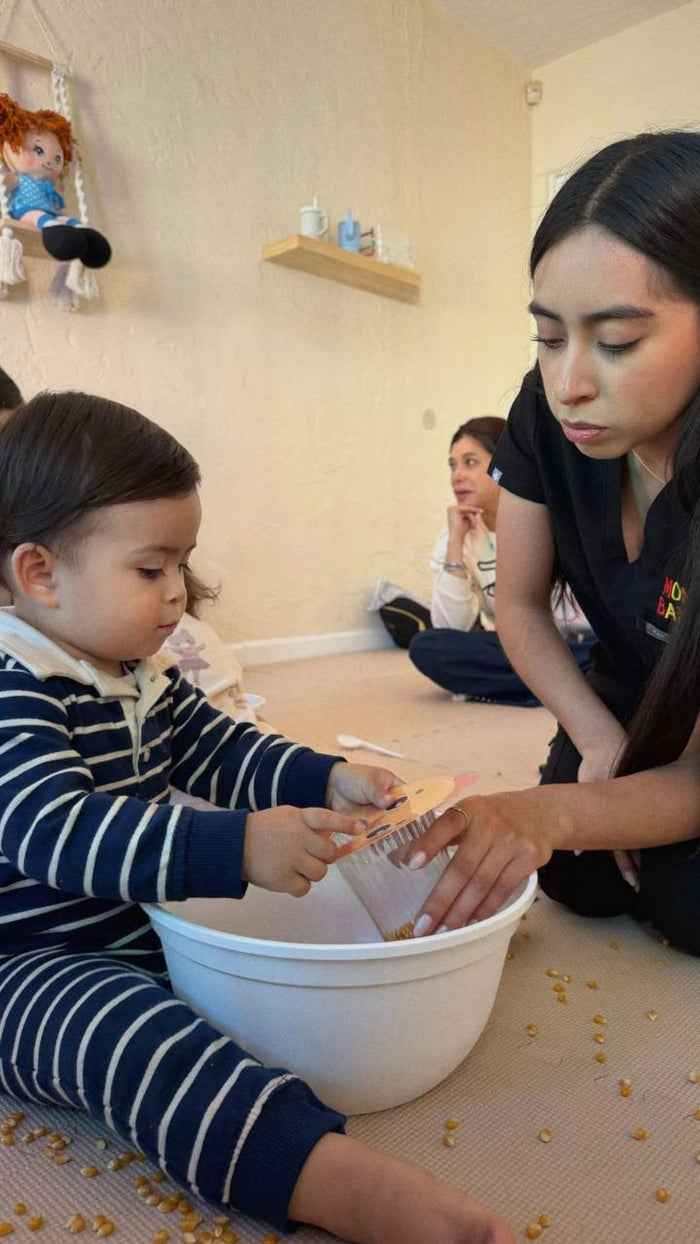 Guía acompañando a un bebé en actividad sensorial