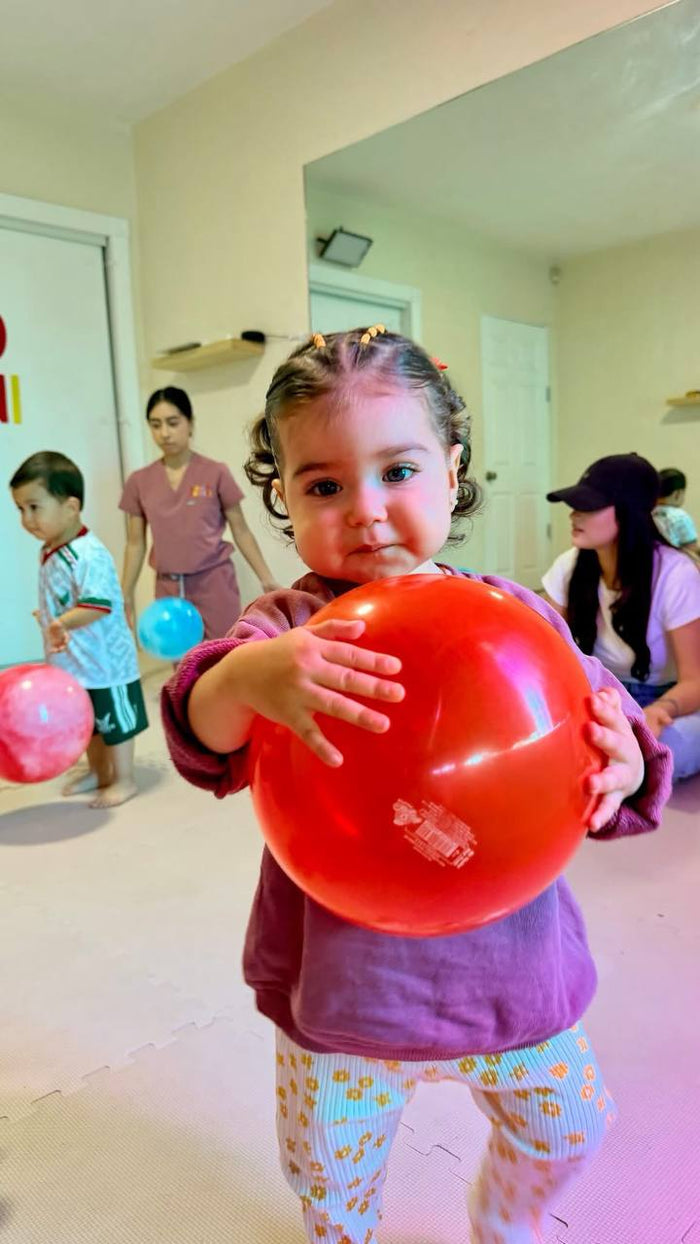 Niña jugando con una pelota roja