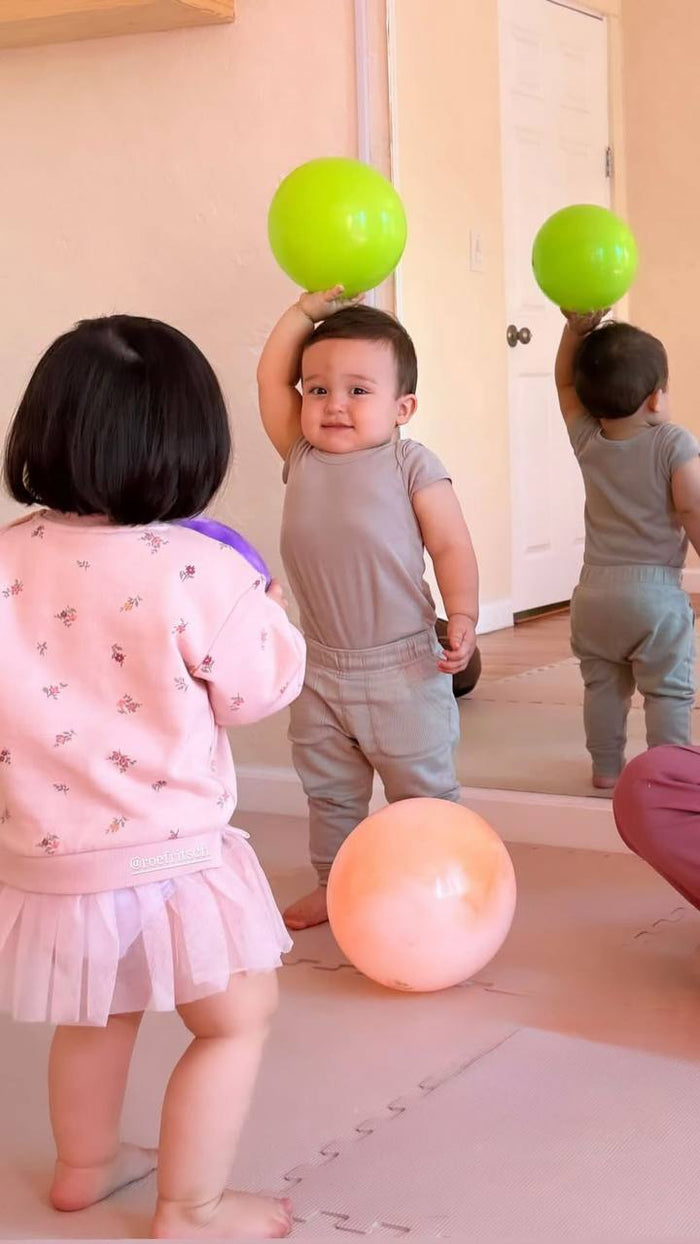Bebés jugando con pelotas frente al espejo